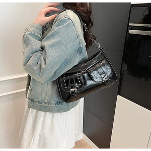 Side view of black patent leather motorcycle bag with silver rivets on shoulder