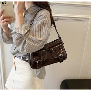 Detail view of a dark brown patent leather underarm bag with silver rivets and buckle