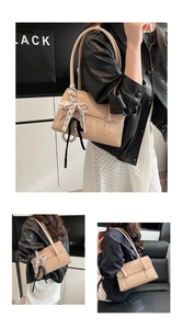 Detail of beige patent leather envelope bag with silk scarf and pearl chain charm