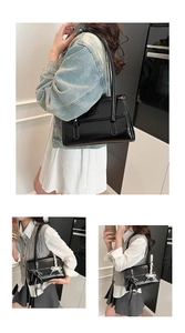 Detail of black glossy patent leather shoulder bag with embossed texture and metal charms