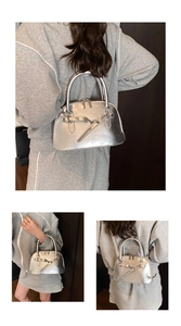 Close-up of silver shell crossbody bag featuring metallic finish and buckle strap detail