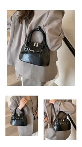 Detail of black leather shell bag with silver buckle and dual zipper closure system