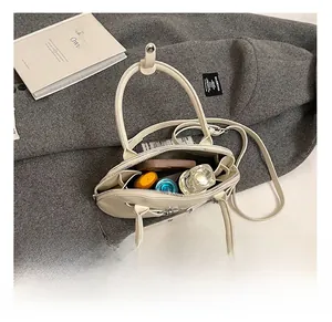 Interior view of the cream shell bag showing spacious capacity for phone and perfume