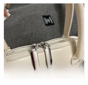 Detail view of smooth off-white leather handbag with premium silver dual zipper hardware