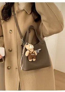Detail of dark brown lychee leather bucket bag with a cute teddy bear charm