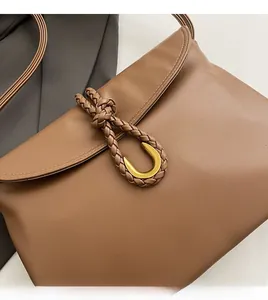 Close-up of brown leather bag featuring woven rope detail and golden metal buckle