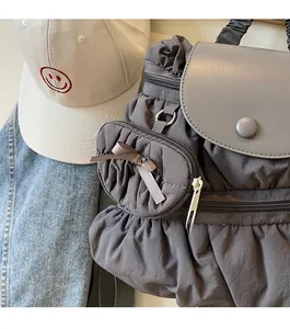 Detail of dark gray pleated drawstring backpack with leather flap and mini bow pouch