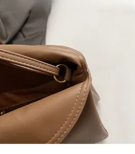 Detail of matte brown leather shoulder bag featuring gold metal rings and precision stitching