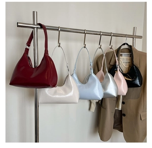 Detailed display of crescent underarm bags in six glossy colors hanging on a metal rack