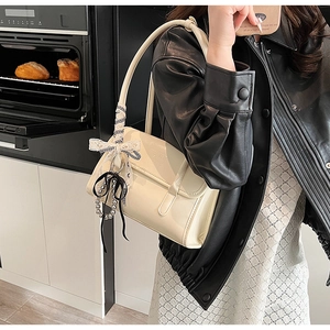 Detail of off-white shoulder bag with checkered bow and silver beads on a model