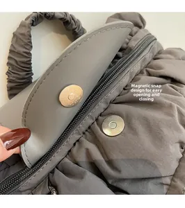 Detailed view of the magnetic snap closure and zipper on a pleated gray fabric backpack