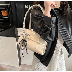 Détail du sac à bandoulière beige avec ruban décoratif et pendentif à perles
