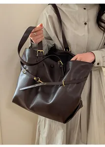 Close-up of vintage dark brown faux leather tote bag with retro gold buckles and ring details
