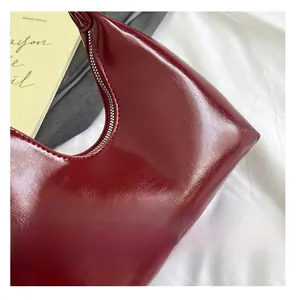 Detailed close-up of wine red patent leather handbag showing fine stitching and glossy texture