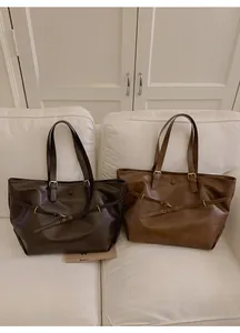Detail of dark caramel and light brown leather tote bags with metal buckle straps