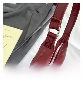 Close-up of the red patent leather bag showing stitching details and silver metal ring
