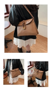 Detail of a brown envelope crossbody bag with a thick woven strap and gold U-buckle