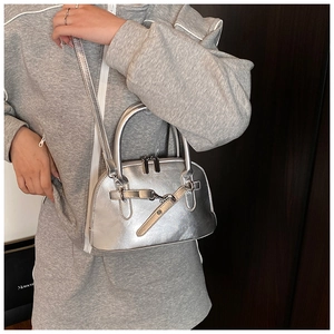Close-up of a metallic silver shell bag with high-shine mirror finish and crossbody strap