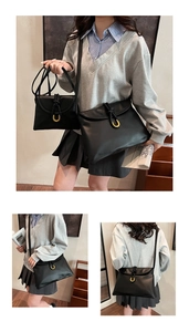 Detail of minimalist black shoulder bag set with woven rope and gold horseshoe buckles