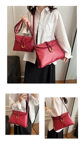 Close-up of matte red leather envelope bag with woven rope detail and gold U-shaped buckle