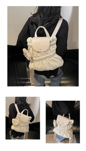 Detail of a beige pleated nylon backpack featuring a soft cloud-like texture and bow charm
