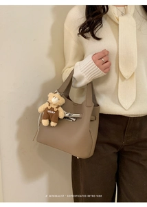 Detail view of elephant grey leather bucket bag with lock closure and cute bear charm