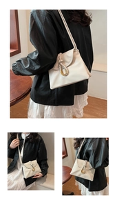 Close-up of cream leather envelope bag with gold horseshoe hardware and woven detail