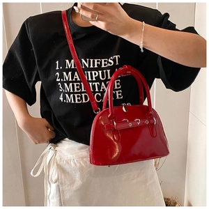 Close-up of red shell-shaped crossbody bag in glossy patent leather with silver hardware