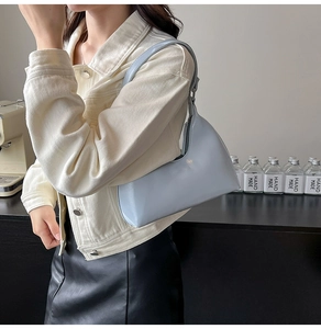 Close-up of a light blue hobo shoulder bag with a glossy finish and crescent moon shape