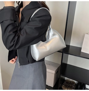 Silver metallic hobo bag worn on shoulder by model with shiny PU material detail