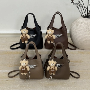 Detail view of four leather bucket bags in various colors with cute bear pendants