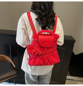 Detail of red pleated backpack featuring drawstring closure and a cute heart bow pendant
