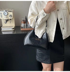 Glossy black crescent shoulder bag styled with a chic denim jacket for an urban look