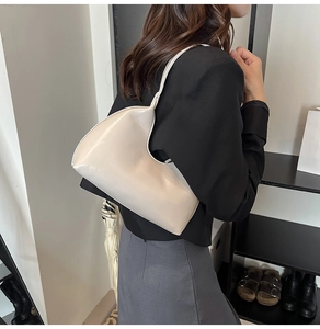 Chic cream-colored hobo bag in polished synthetic leather shown worn on the shoulder