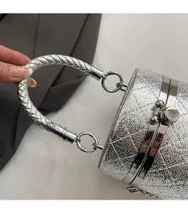 Close-up of silver quilted bucket bag with woven handle and spherical metal clasp lock