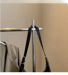 Detail of black leather tote bag strap with silver metal ring on a display stand
