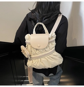 Gedetailleerd beeld van beige geplooide rugzak met magnetische klep en mini-tasje erbij