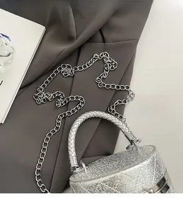 Detail of silver sequined bucket bag featuring metallic chain and woven top handle