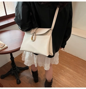 Detail of cream PU leather shoulder bag with woven strap and gold U-shaped buckle