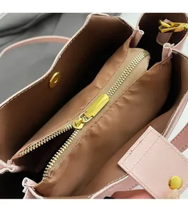 Close-up of pink bucket bag interior showing smooth gold zipper and brown lining