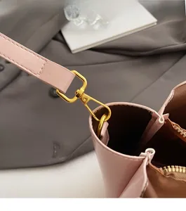 Detail of golden lobster clasp hardware and zipper on pink oil wax leather bucket bag