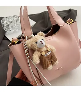 Close-up of pink leather bucket bag with cute bear charm and adjustable shoulder strap
