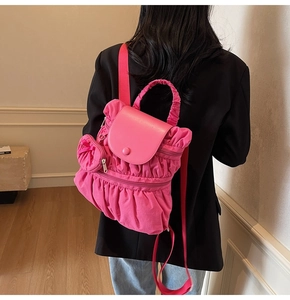 Detail of a pink pleated backpack with a matching mini round coin purse and metal snap