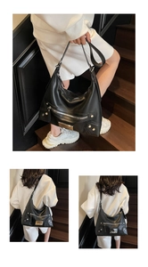 Détail du sac hobo en cuir noir avec fermetures éclair argentées, rivets et plaque métal