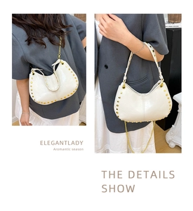 Detail of white glossy leather shoulder bag with gold rivets and chain strap
