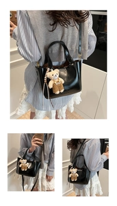 Detail of black glossy bucket bag with a cute teddy bear charm and letter embossing