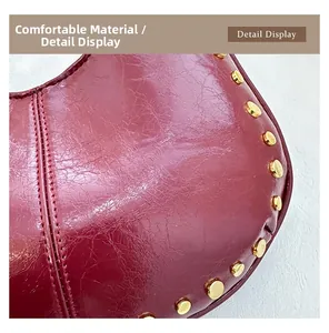 Close-up of dark red wrinkled leather handbag featuring gold stud rivets and stitching