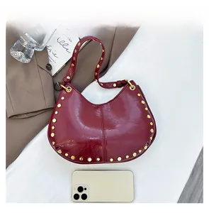 Detailed view of burgundy wine hobo bag with gold rivet studs and glossy finish