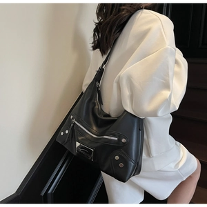 Close-up of black tote bag featuring silver rivets and metal zipper details