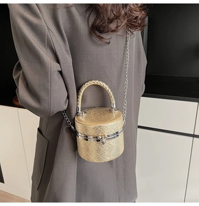 Detail of a gold glitter cylindrical bucket bag with quilted texture and chain strap